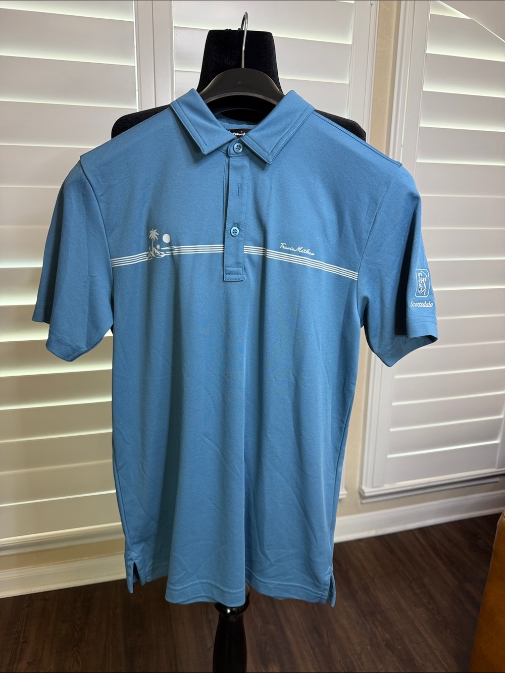 Travis Mathew Light Blue Polo with White Chest Stripe and Palm Graphic